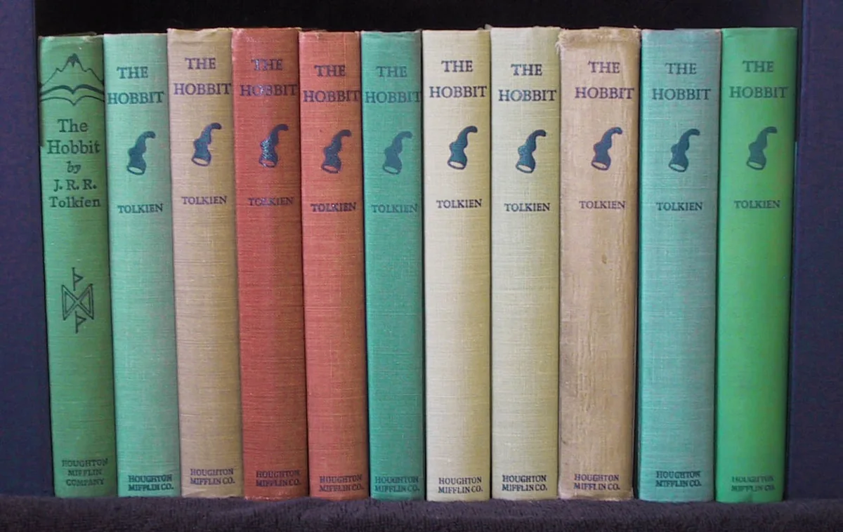 A row of cloth-bound copies of The Hobbit in assorted colours standing spine out on a shelf.